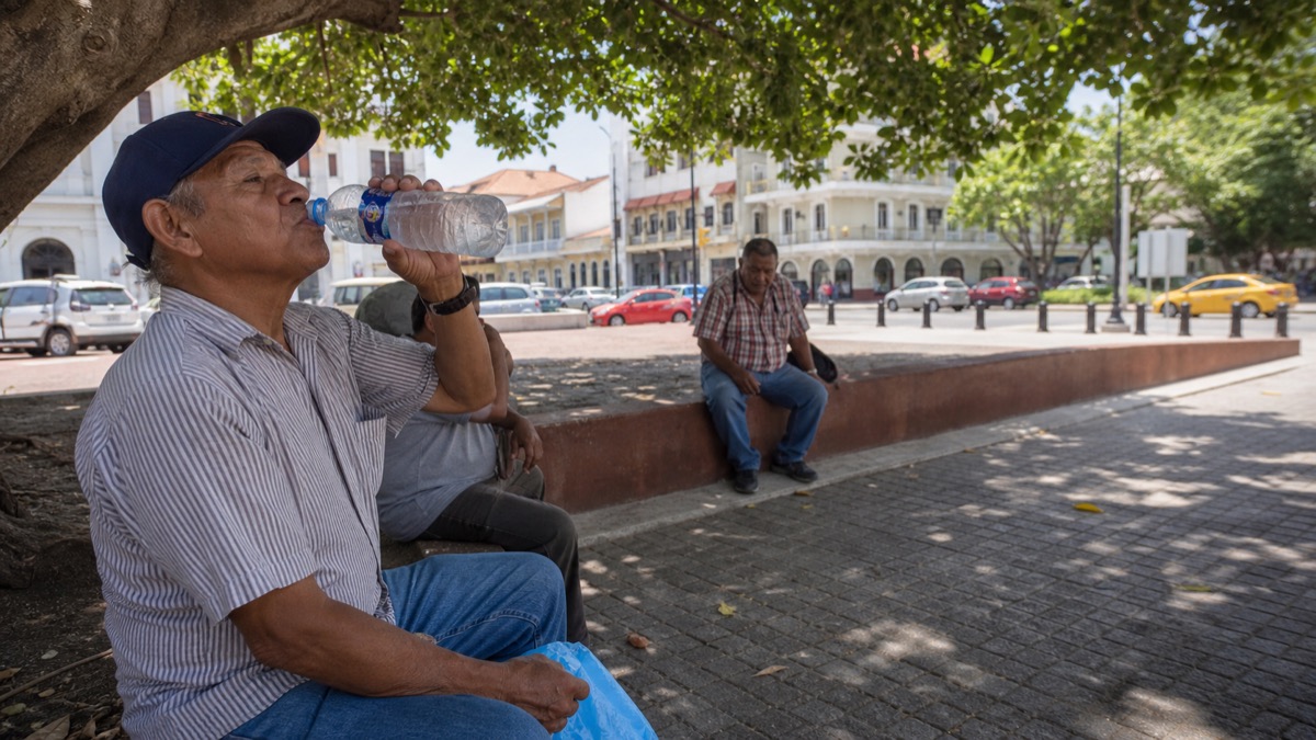 Panama residents drinking water and resting in shade during a hot sunny afternoon