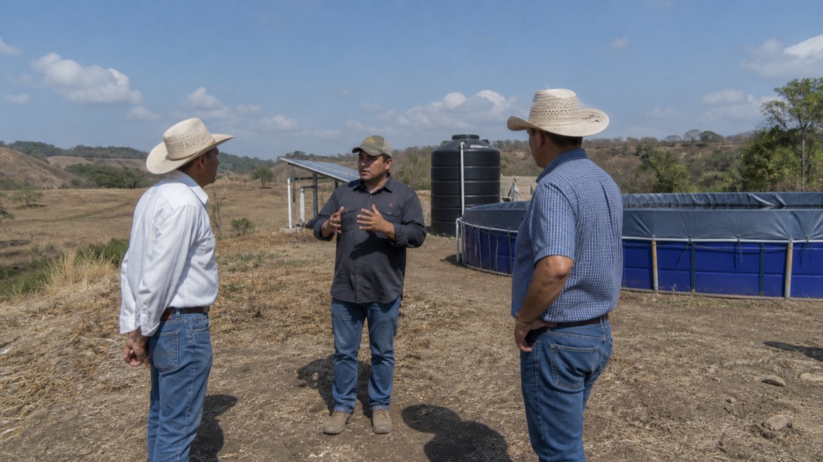 farm producers meeting beside dry fields and water storage equipment in rural Panama, no readable signs