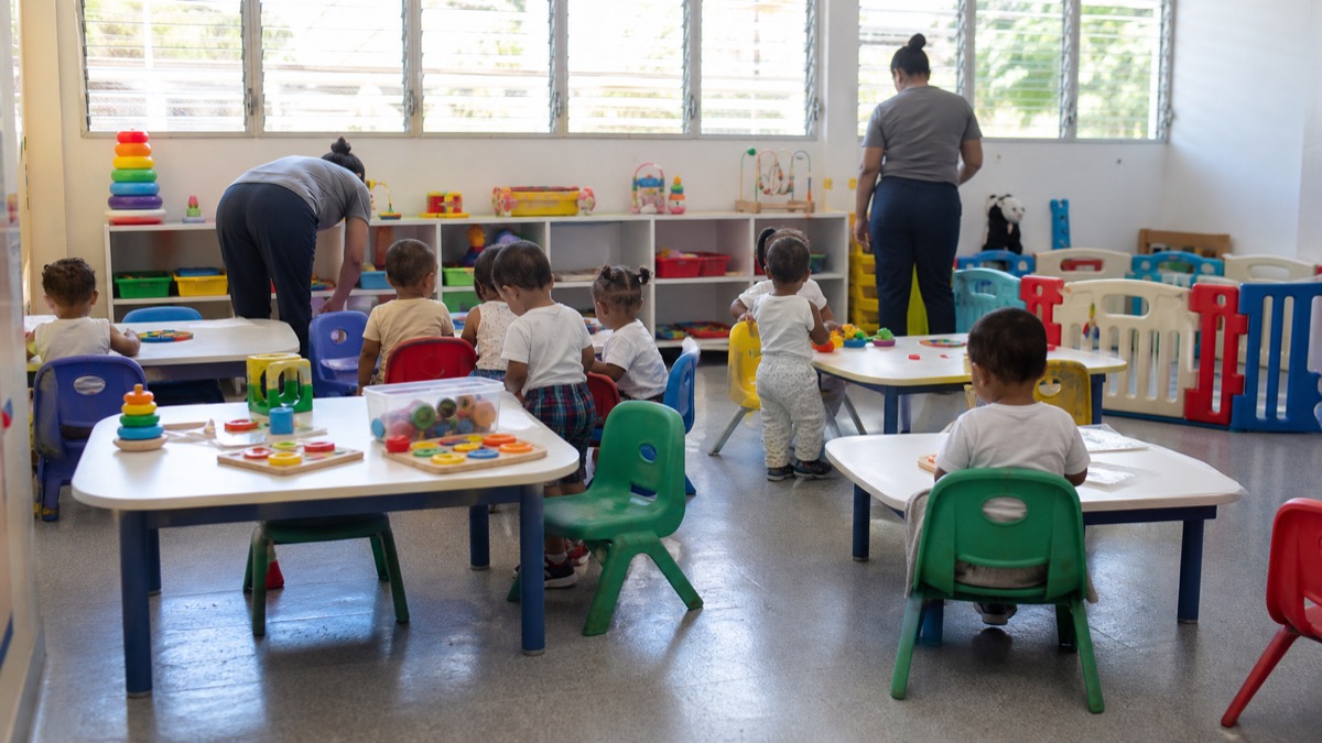 bright Panamanian early-childhood centre classroom with educational toys and caregivers, faces not identifiable