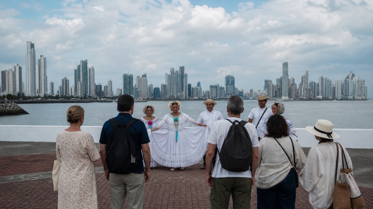 wide editorial photo of Panama City skyline and visitors at a cultural welcome event, no logos or readable signs