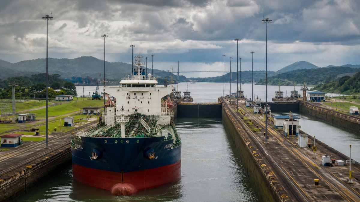 large cargo vessel approaching Panama Canal locks under cloudy tropical sky, documentary maritime scene