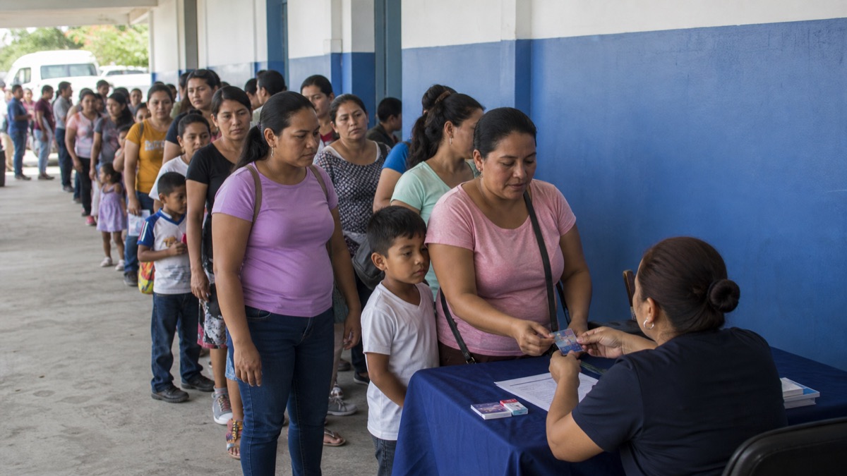 families waiting in an orderly line at an education-benefit card distribution point in Panama, no readable banners