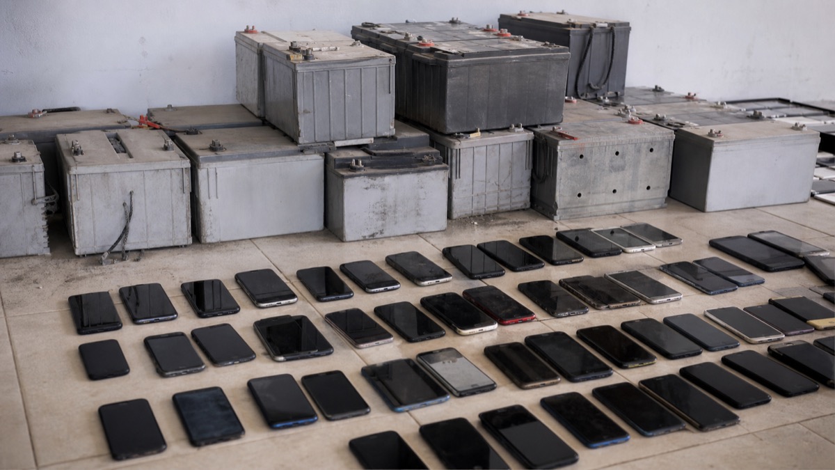 recovered telecom backup batteries and mobile phones arranged as police evidence, no labels