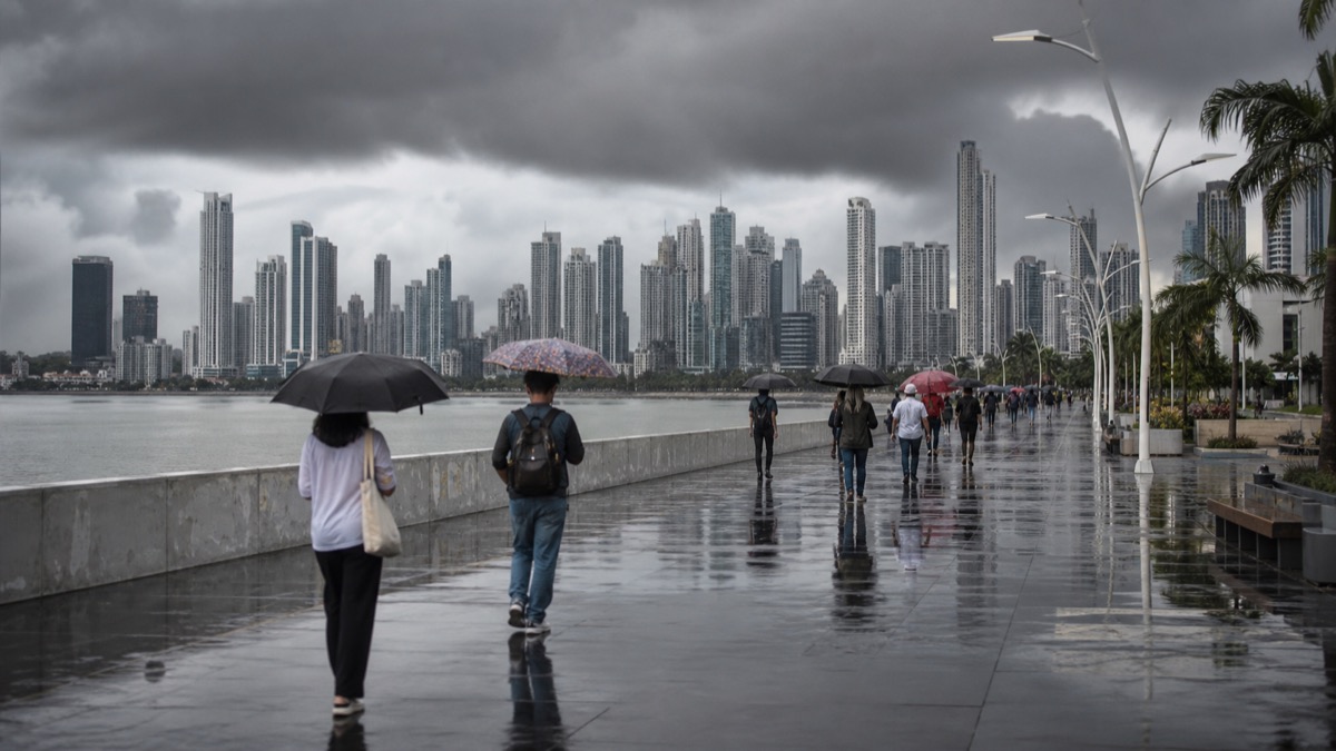 rain clouds over Panama City with wet streets and pedestrians carrying umbrellas, natural news photo