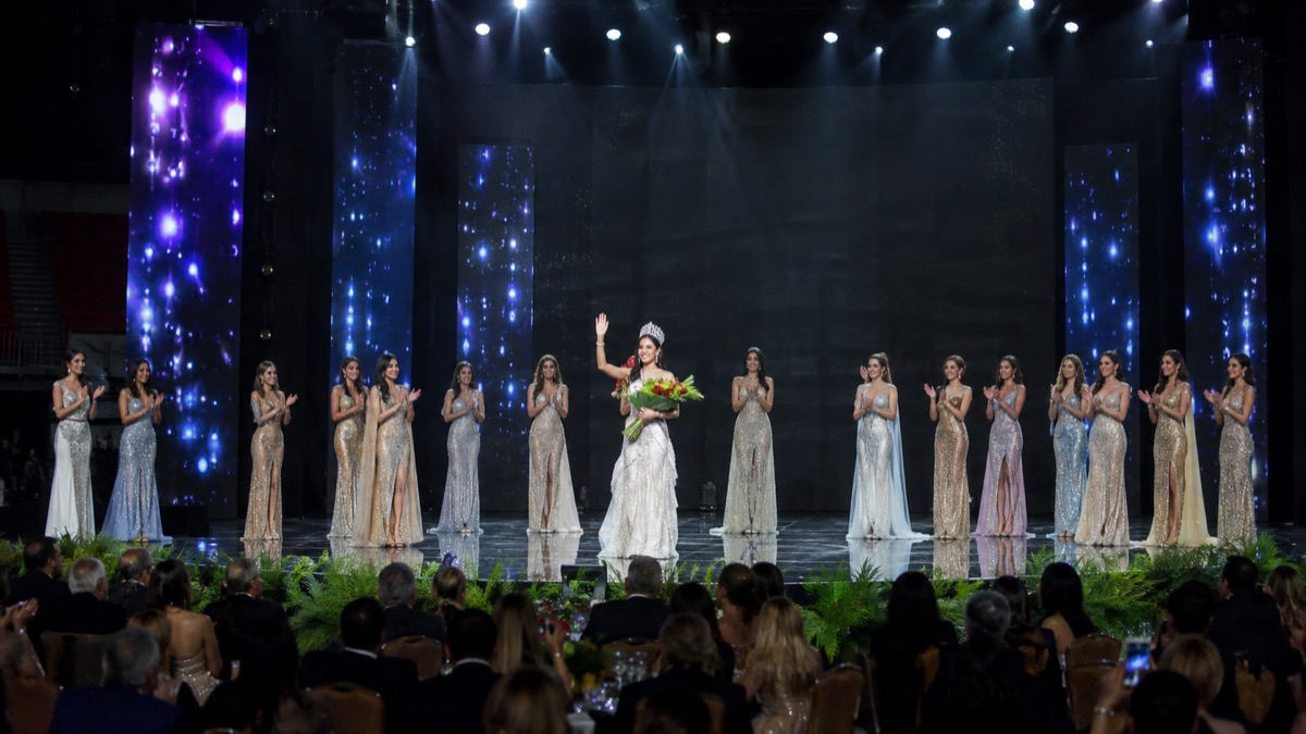elegant national pageant finale on a large Panama arena stage with a newly crowned contestant seen from a respectful distance, generic faces and no logos or text