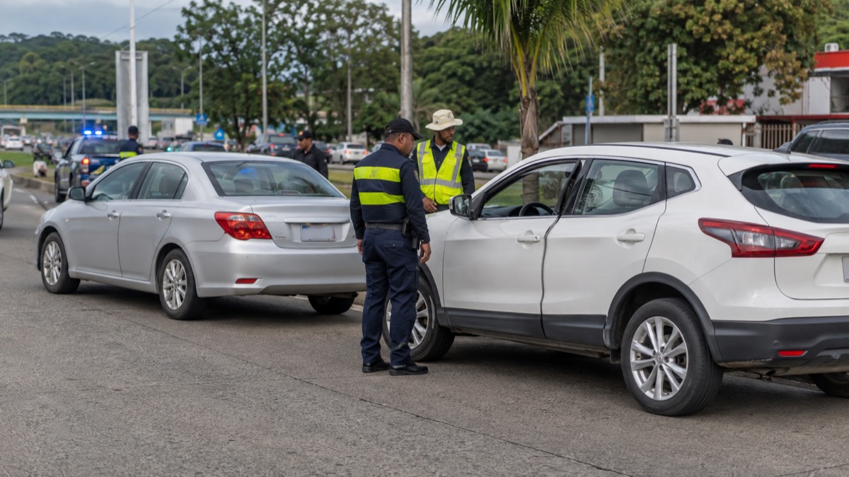 traffic-safety response at a minor urban road collision in San Miguelito Panama, two stopped cars with responders nearby, no injured people or visible damage